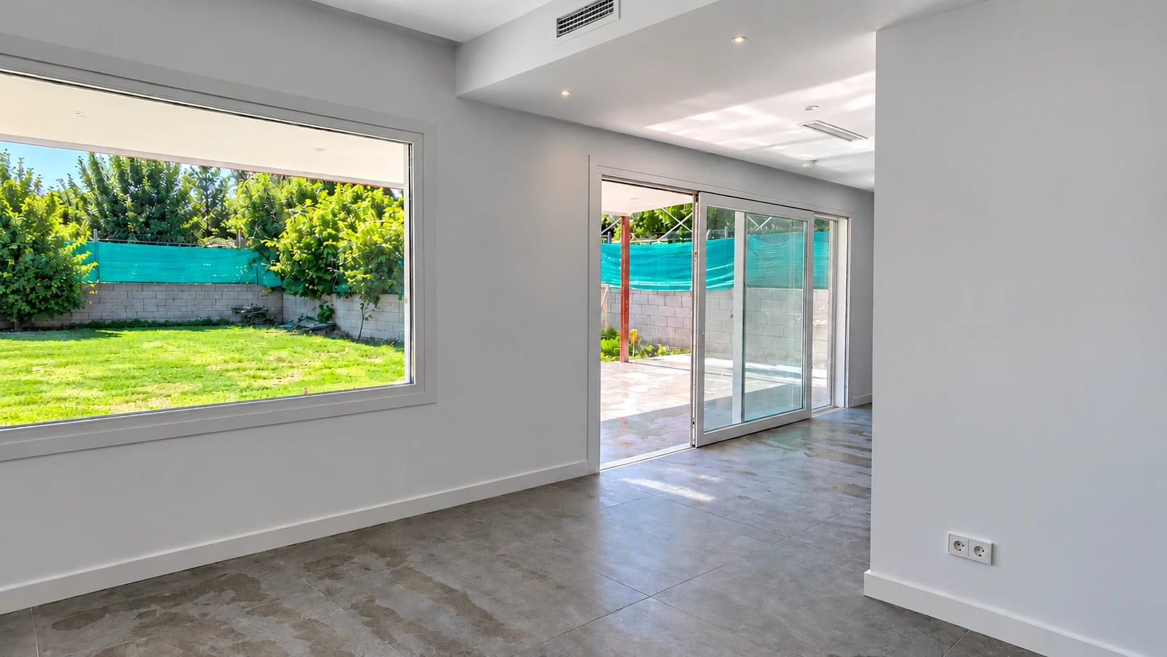 Estancia blanca con grandes ventanas abiertas visualmente al jardín