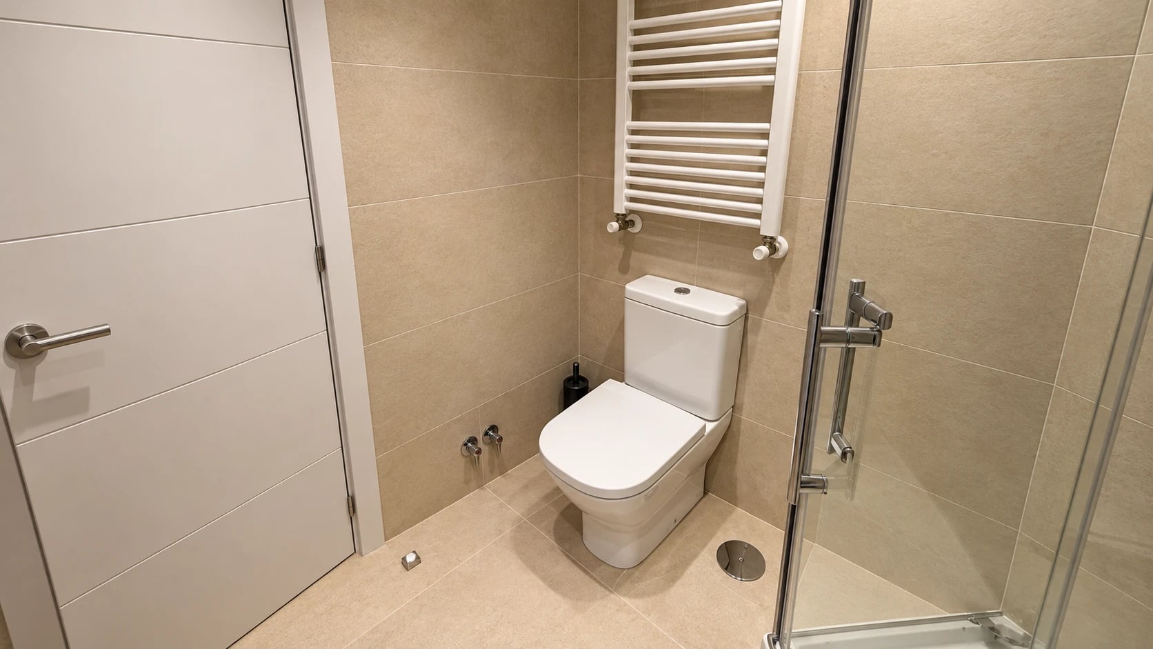 Sanitario, radiador toallero y puerta blanca en un baño renovado