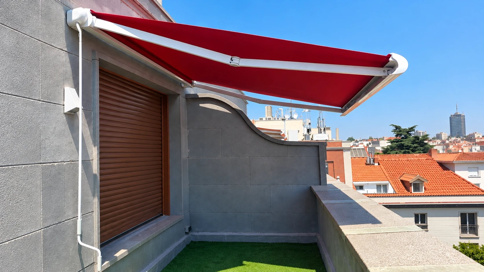 Toldo rojo desplegado sobre una terraza con revestimiento gris y vistas a Madrid